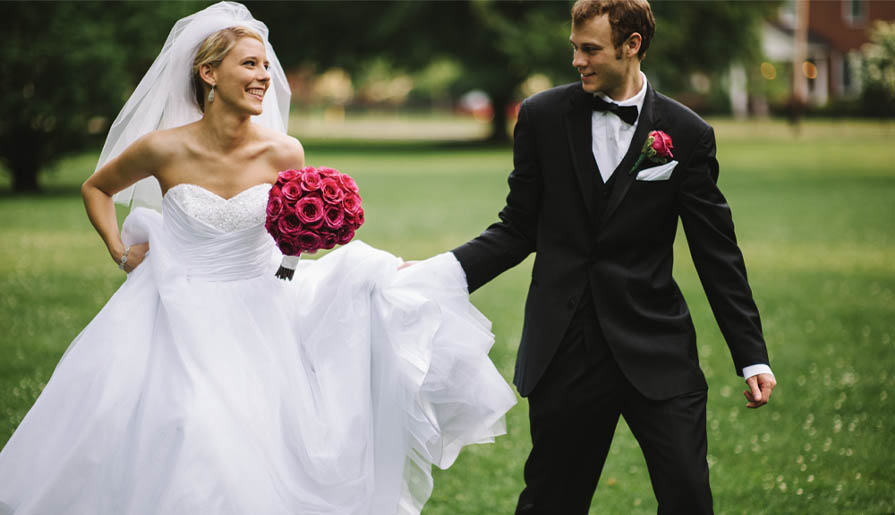 A bride in a flowing white gown holds a bouquet of vibrant pink roses
