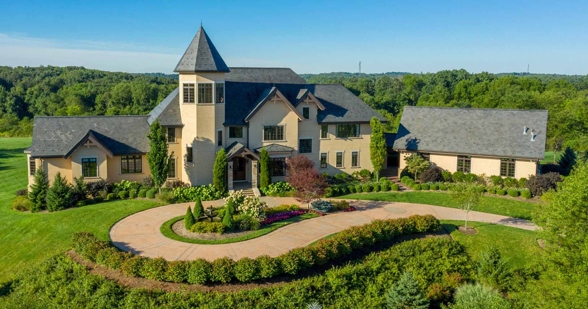 A large, elegant house with beige walls and a slate-gray roof